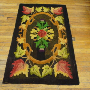 Dark hooked rug featuring a colorful floral medallion and autumn leaves on a light plank wooden floor.