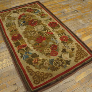 A rectangular rug featuring a dense floral pattern in red, olive, and cream is placed on distressed wooden floors.