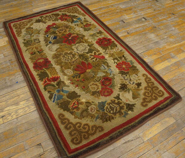 A rectangular rug featuring a dense floral pattern in red, olive, and cream is placed on distressed wooden floors.
