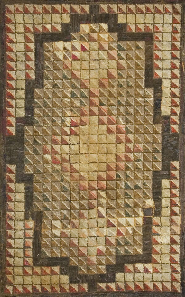 Textured, geometric rug featuring raised pyramid squares and a dark stepped border in tan, red, and brown tones.