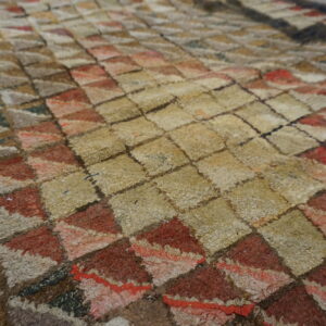 Shaggy rug texture with a geometric pattern in beige, rust, brown, and muted grey colors.
