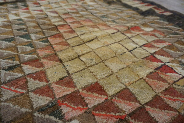 Shaggy rug texture with a geometric pattern in beige, rust, brown, and muted grey colors.