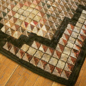 Muted rug with high-pile cream, terracotta, and brown geometric patterns on distressed wood flooring.