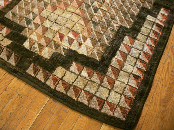 Muted rug with high-pile cream, terracotta, and brown geometric patterns on distressed wood flooring.