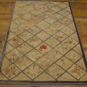 Beige rectangular rug with a floral diamond pattern lying on glossy rustic wooden flooring.
