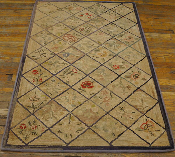 Beige rectangular rug with a floral diamond pattern lying on glossy rustic wooden flooring.