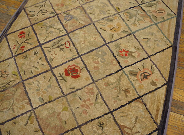 A beige rug features a segmented diamond grid with dense floral motifs in muted reds and greens on wood flooring.