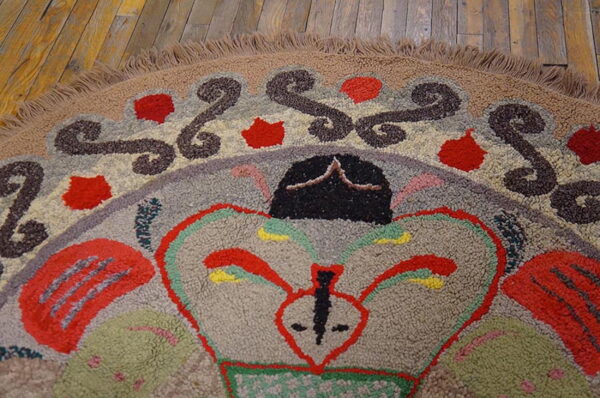 High-pile multicolor hooked rug with abstract shapes and swirls rests on distressed wooden floorboards.