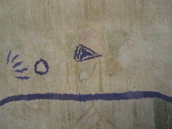 Textured beige rug detail with purple abstract elements, a horizontal stripe, and faint patches of green and pink.