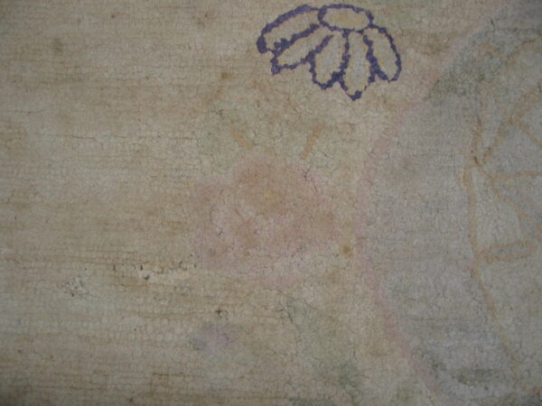 Distressed, crackled texture on a pale rug showing a faded purple daisy outline and pink remnants.