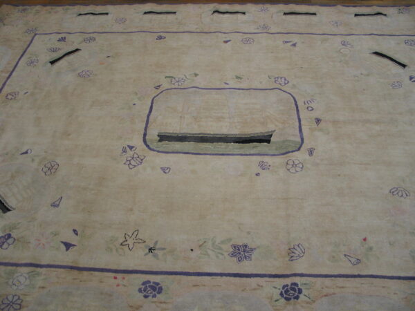 Low-pile beige rug with a central purple-outlined ship and scattered floral motifs on wood flooring.