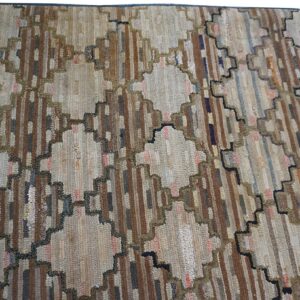 Muted brown, beige, and blue stripes form geometric diamond patterns with stepped, dark outlines on this rug.