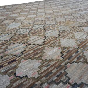 Textured low pile rug featuring a geometric pattern of light neutral patches and dark striped blocks.