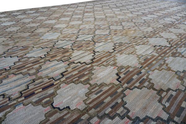 Textured low pile rug featuring a geometric pattern of light neutral patches and dark striped blocks.