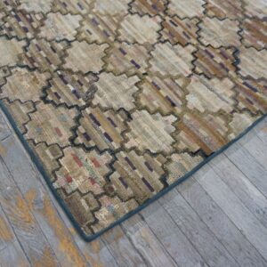 Textured beige rug with a dark zigzag octagonal pattern rests on distressed gray wood flooring.