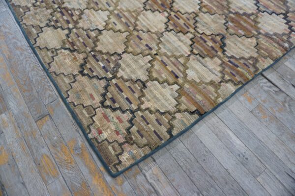 Textured beige rug with a dark zigzag octagonal pattern rests on distressed gray wood flooring.