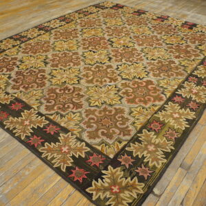 Low pile rug with repeating geometric floral patterns in brown, gold, and deep green on light plank wood floors.