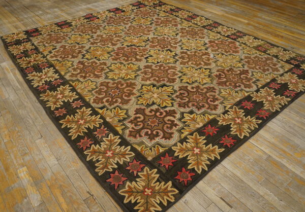 Earth-toned rug with a geometric floral design and a dark wide border rests on rustic wood flooring.
