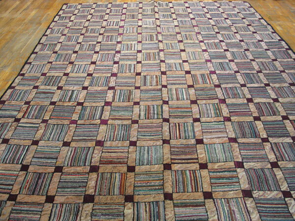 Large grid rug with tan borders and multi-colored striped blocks, connected by purple squares on a wood floor.