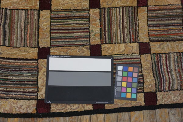 Patchwork rug with nubby texture displays tan, maroon, and multi-colored striped blocks on wood flooring.