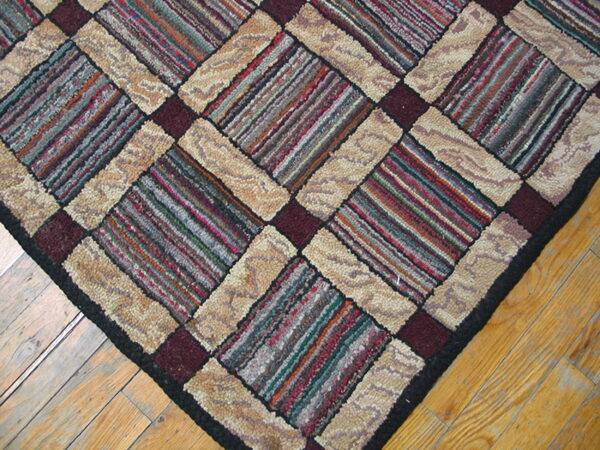 A textured diagonal patterned rug with multicolored striped blocks and looped beige borders on wood flooring.