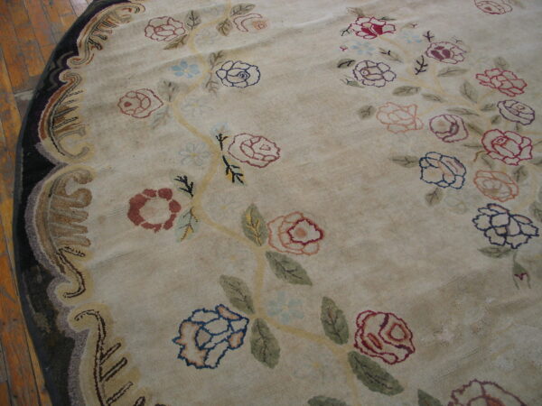 Round beige rug with scattered pink, blue, and red roses, bordered by dark scrollwork on wood.