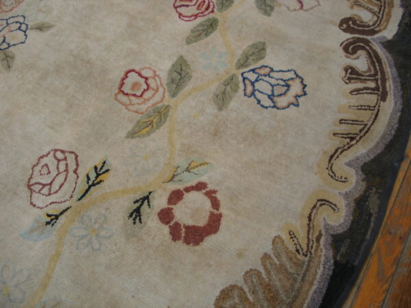 Textured beige rug with scattered colorful roses and vines bordered by dark, complex scrolls.