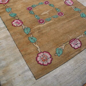 Brown, ribbed rug with pink roses and green leaves, surrounded by a light nubby loop border.