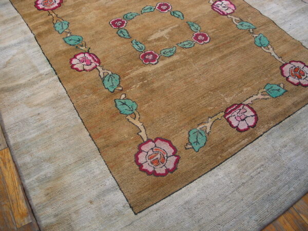 Brown, ribbed rug with pink roses and green leaves, surrounded by a light nubby loop border.