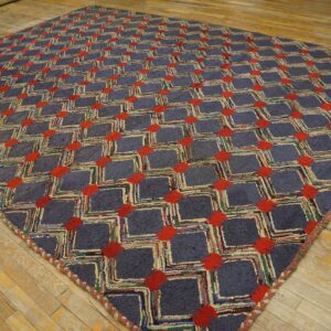 A textured square rug with blue-gray lattice and red geometric accents rests on a distressed wood floor.