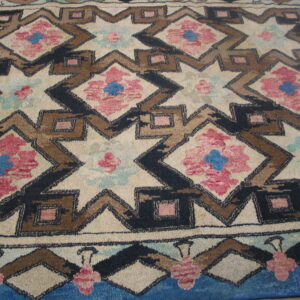 Geometric rug pattern featuring large cream stars outlined in black and brown surrounding pink and blue floral details.