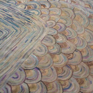 Muted pastel rug detail features a raised texture with blue chevron stripes and overlapping beige and purple scalloped shapes.