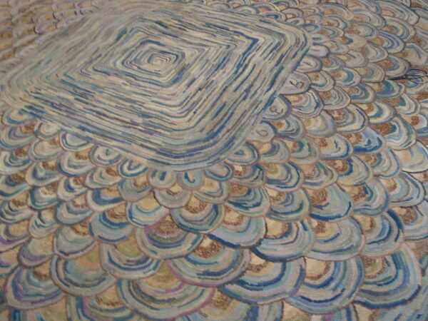 Textured rug with blue, tan, and brown overlapping scales surrounding a striped diamond center.