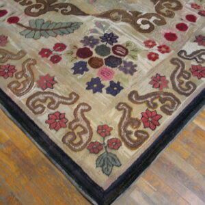 Textured beige rug featuring complex floral and scrollwork designs in maroon, purple, and green on wood planks.