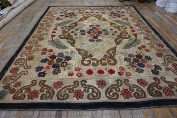 Low-pile rug with colorful floral and brown scroll design on a light beige background over wood floor.