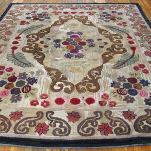 Textured rug featuring a dense, colorful floral and scroll pattern in beige, purple, and maroon on wood plank flooring.