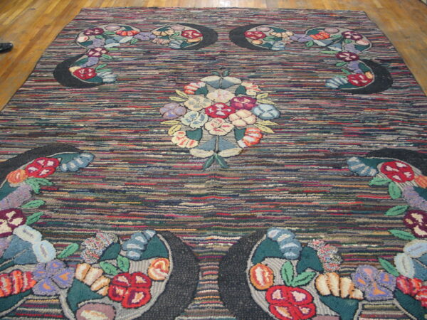 Hooked rug with multicolored floral bouquets arranged on a dark, horizontally striated background over wood flooring.