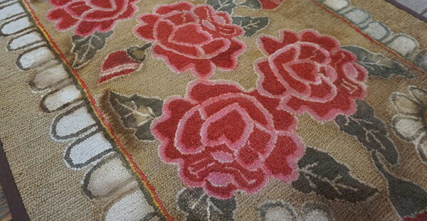 Textured tan rug featuring large red and pink roses with muted gray-green leaves.
