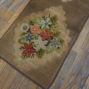 Brown looped rug with a scalloped floral medallion displaying multicolored flowers on light plank wood flooring.