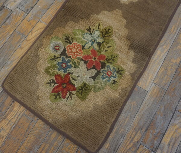 Brown looped rug with a scalloped floral medallion displaying multicolored flowers on light plank wood flooring.