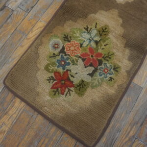 Brown hooked runner rug displaying a red, white, blue, and green floral bouquet on worn wood.
