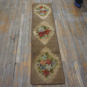 Brown runner rug with three multi-colored floral medallions lying on distressed wood planks.
