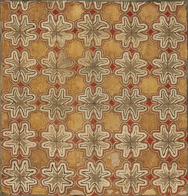 Textured tan rug with repeated star-like motifs outlined in red, gray, and cream colors.
