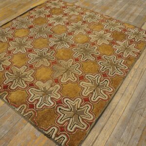 Textured ochre rug featuring red and beige repeating starburst designs on worn wood flooring.