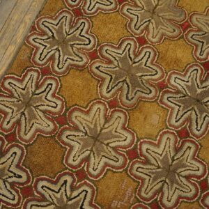 Repeating stylized star motifs in red, gray, and beige set against a golden yellow background on wood flooring.