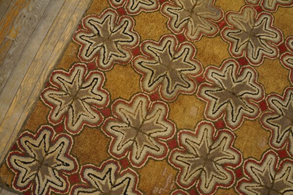 Repeating stylized star motifs in red, gray, and beige set against a golden yellow background on wood flooring.