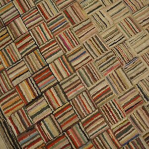 A multi-colored strip rug with a shaggy texture and a basketweave lattice pattern on light wooden floors.