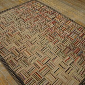 A textured multicolored rug featuring striped rectangular blocks arranged in a diagonal pattern on worn hardwood flooring.