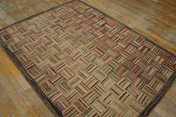 A textured multicolored rug featuring striped rectangular blocks arranged in a diagonal pattern on worn hardwood flooring.