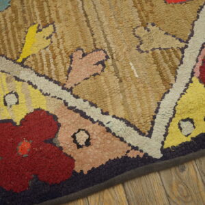 A high-texture rug with abstract floral patterns in red, yellow, beige, and purple on wide wood planks.